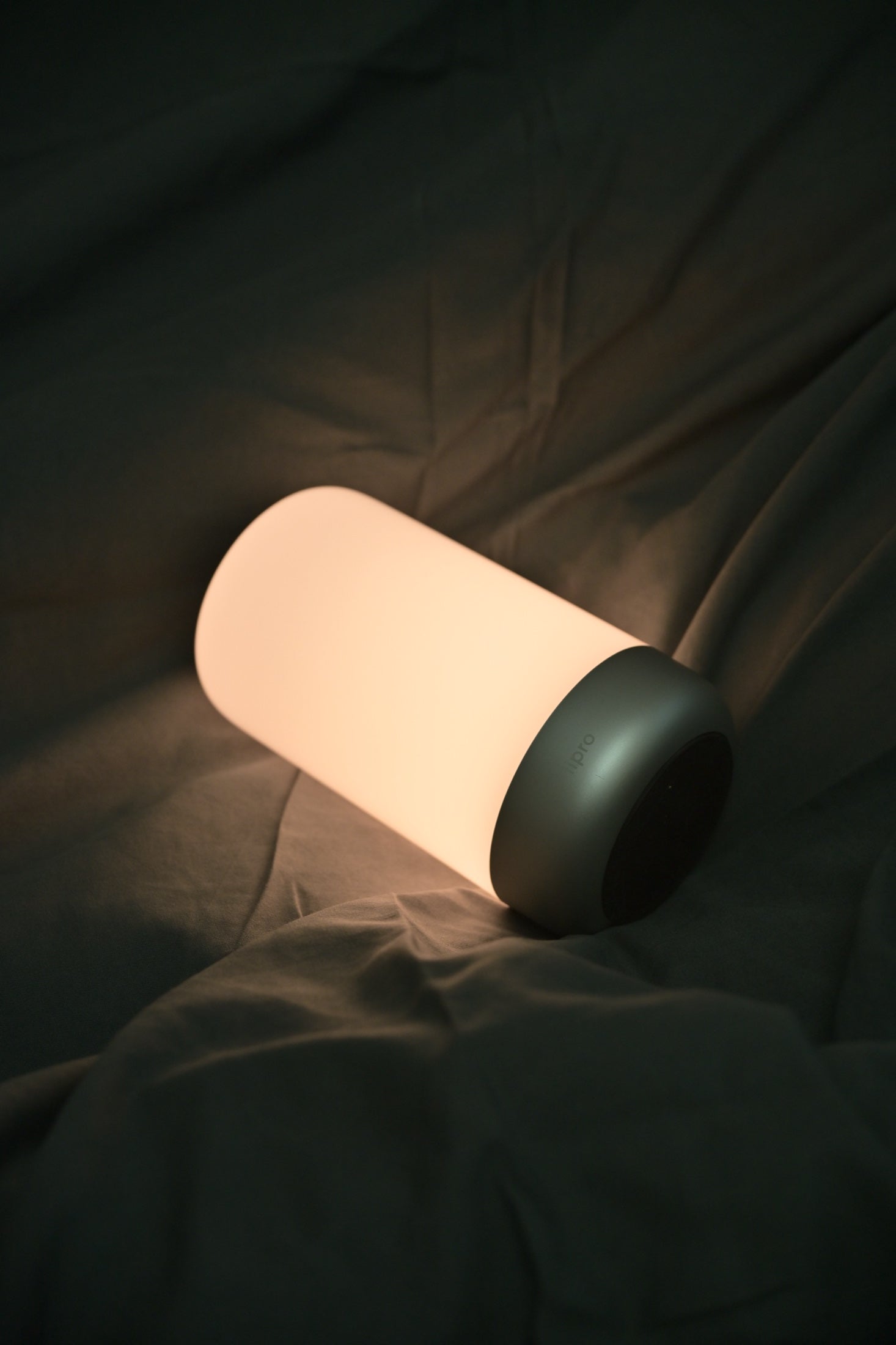 The illuminated diffuser and metal base of Sleep Light resting on fabric